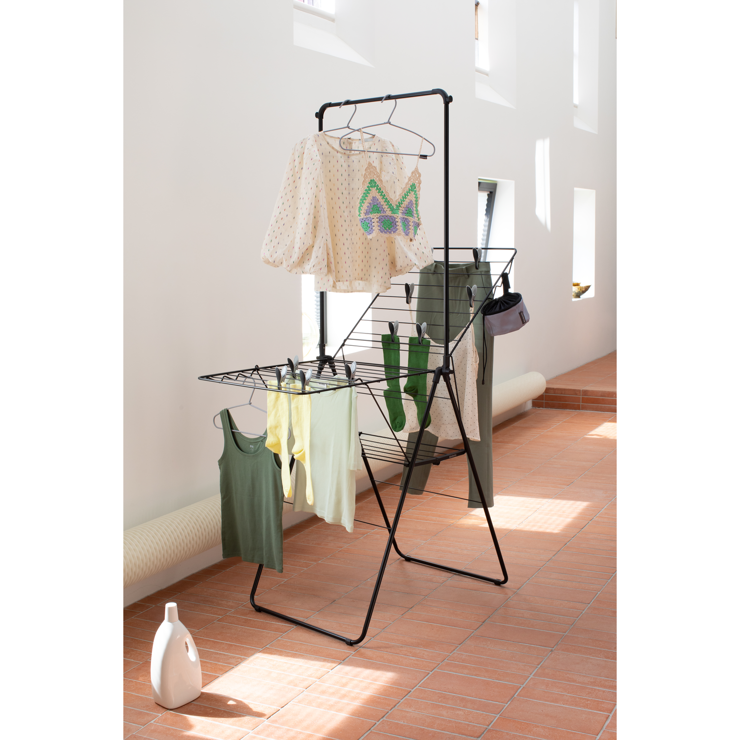A black drying rack with clothes hanging on it.