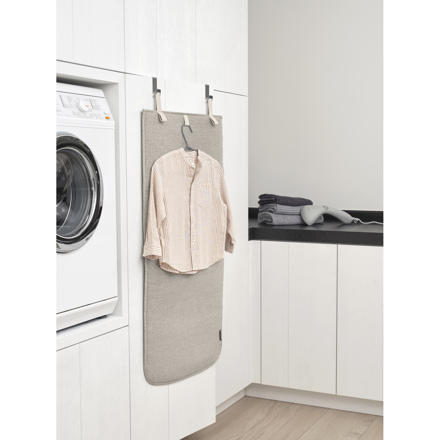 Une chemise accrochée sur une planche à repasser dans une buanderie.