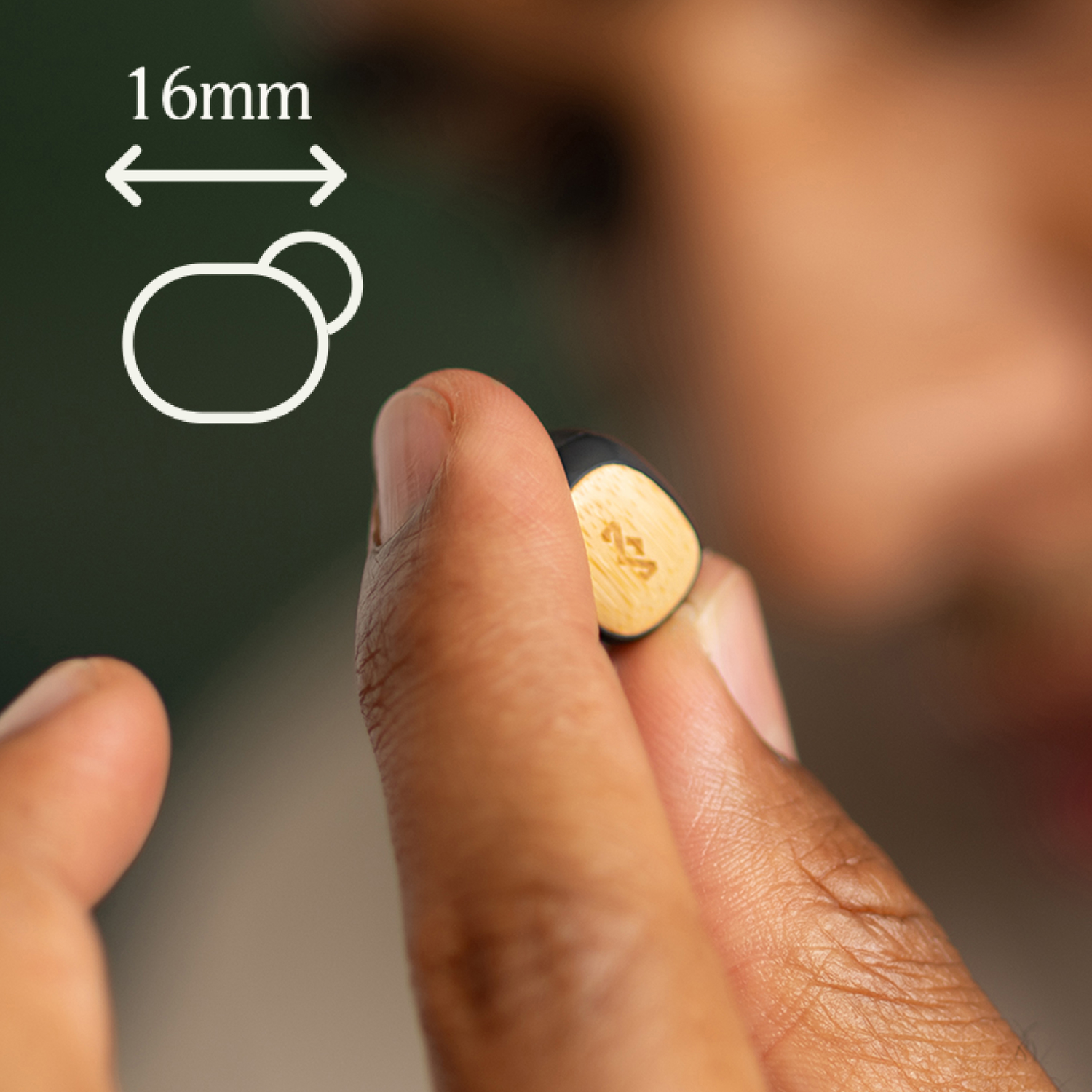 Person holding a small earbud. A white outline of the earbud shape with 16mm measurement is shown.