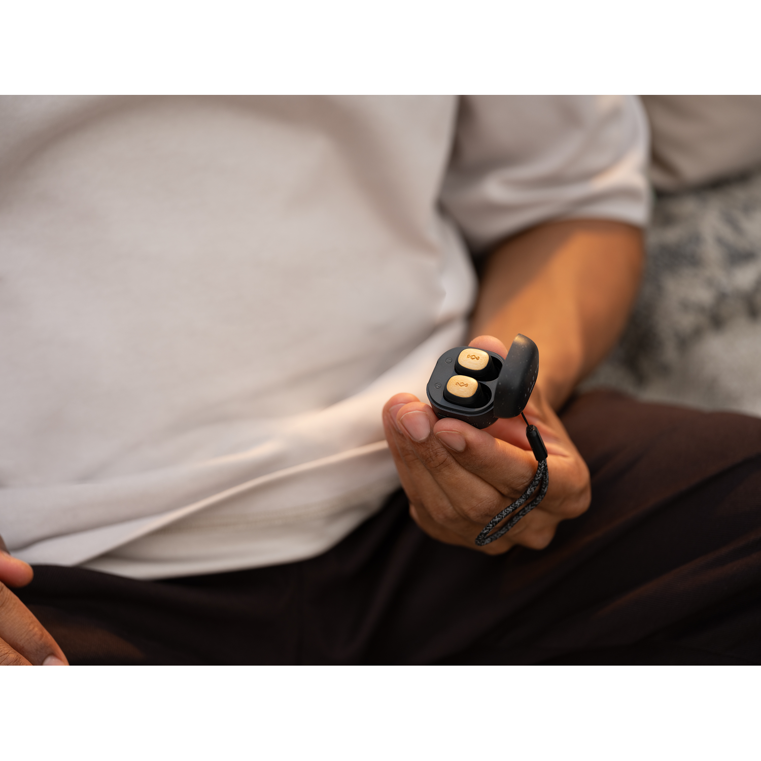 Person holding an open case with two small, gold earbuds.