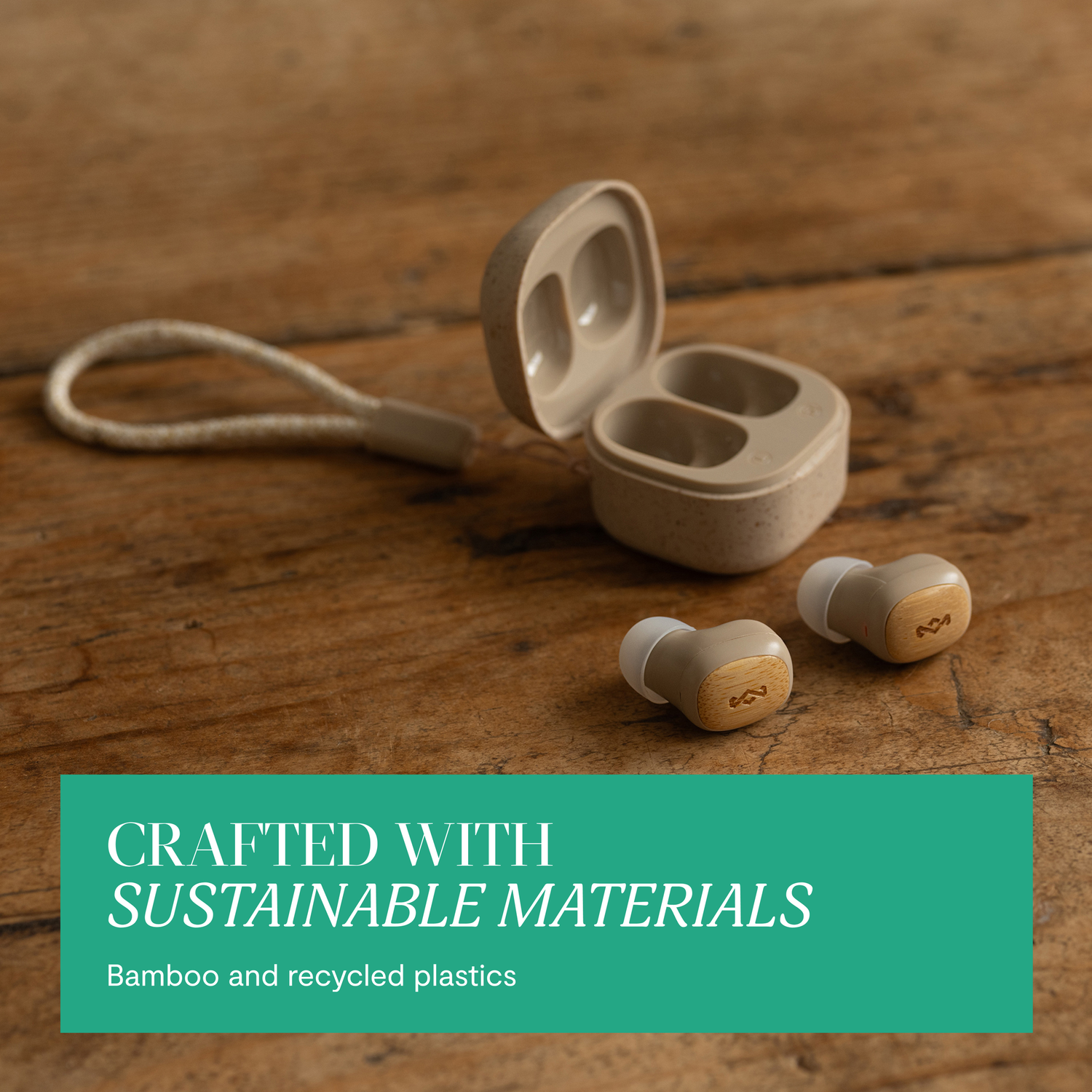 Earbuds and case on wood. Tan and beige colors. Text: Crafted with Sustainable Materials.