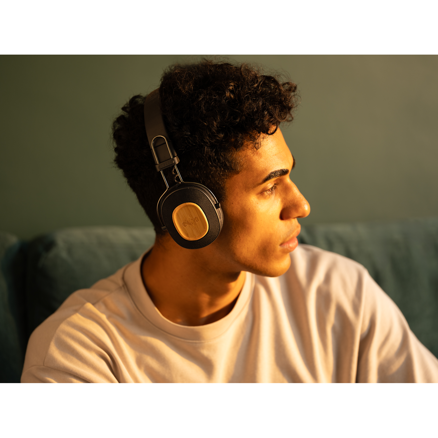 A man wearing black headphones with wooden accents. He is looking to the right.