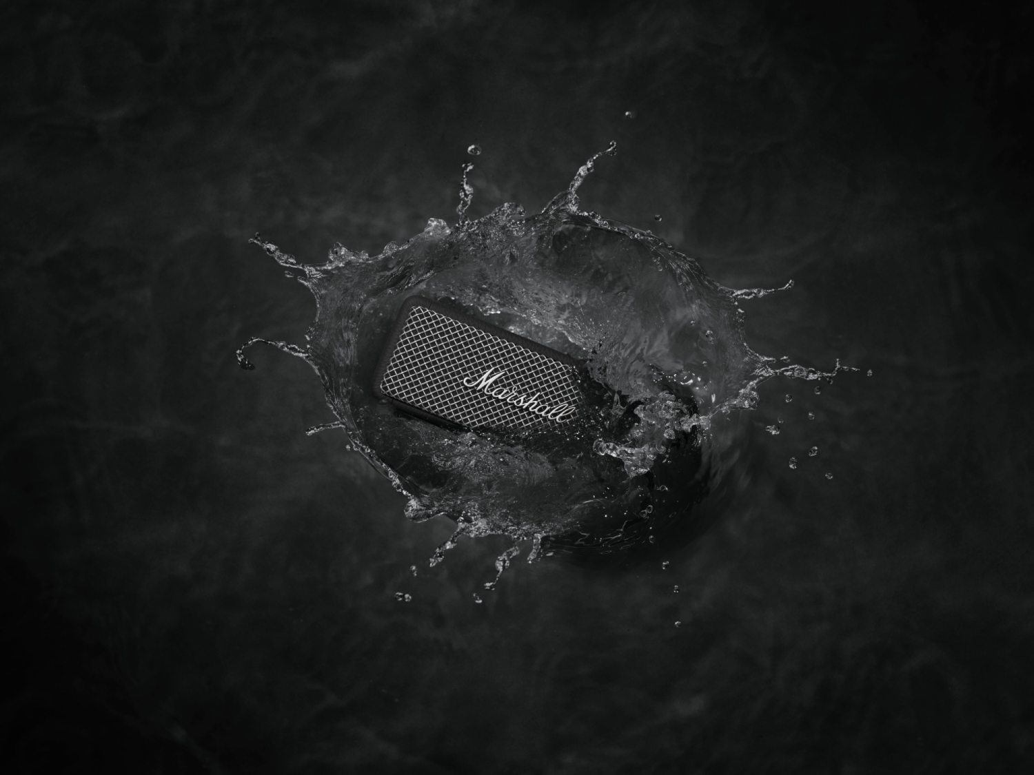 Un altavoz sumergido en agua, creando un chapoteo. Fondo oscuro.