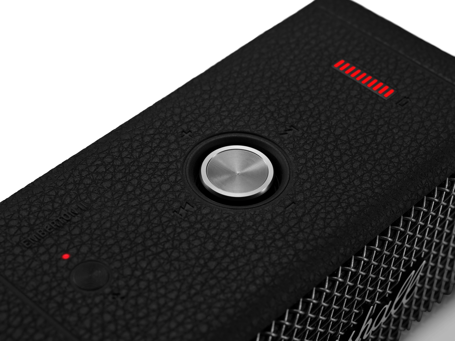 Altavoz negro con botón plateado y luz roja, primer plano.