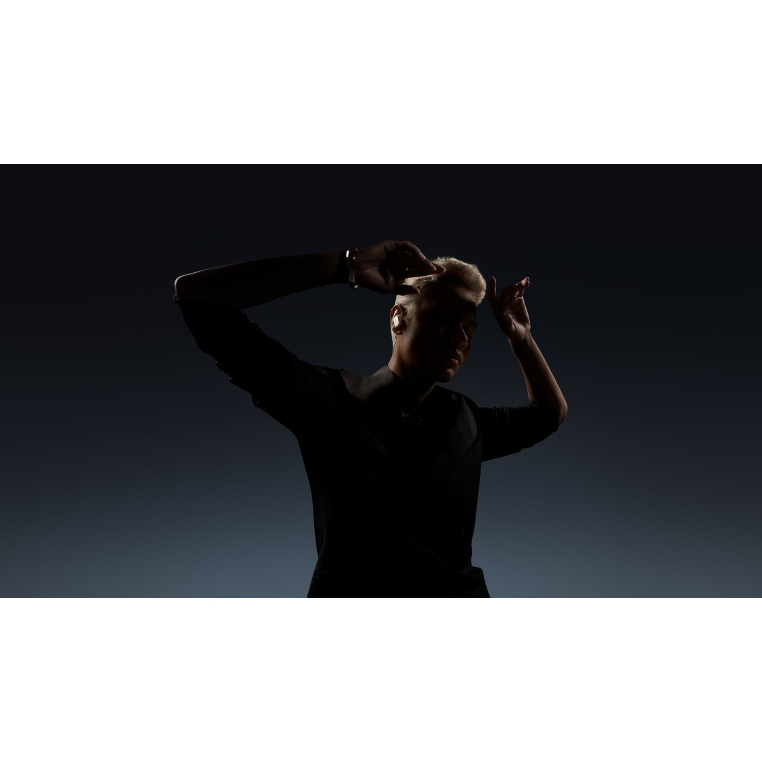 Una persona in silhouette, mani vicino alla testa, indossa orecchini d'oro, su uno sfondo blu sfumato.