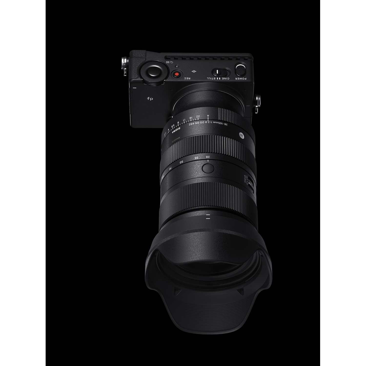Fotocamera nera con obiettivo montato. L'obiettivo ha un paraluce. La fotocamera è su una superficie nera.