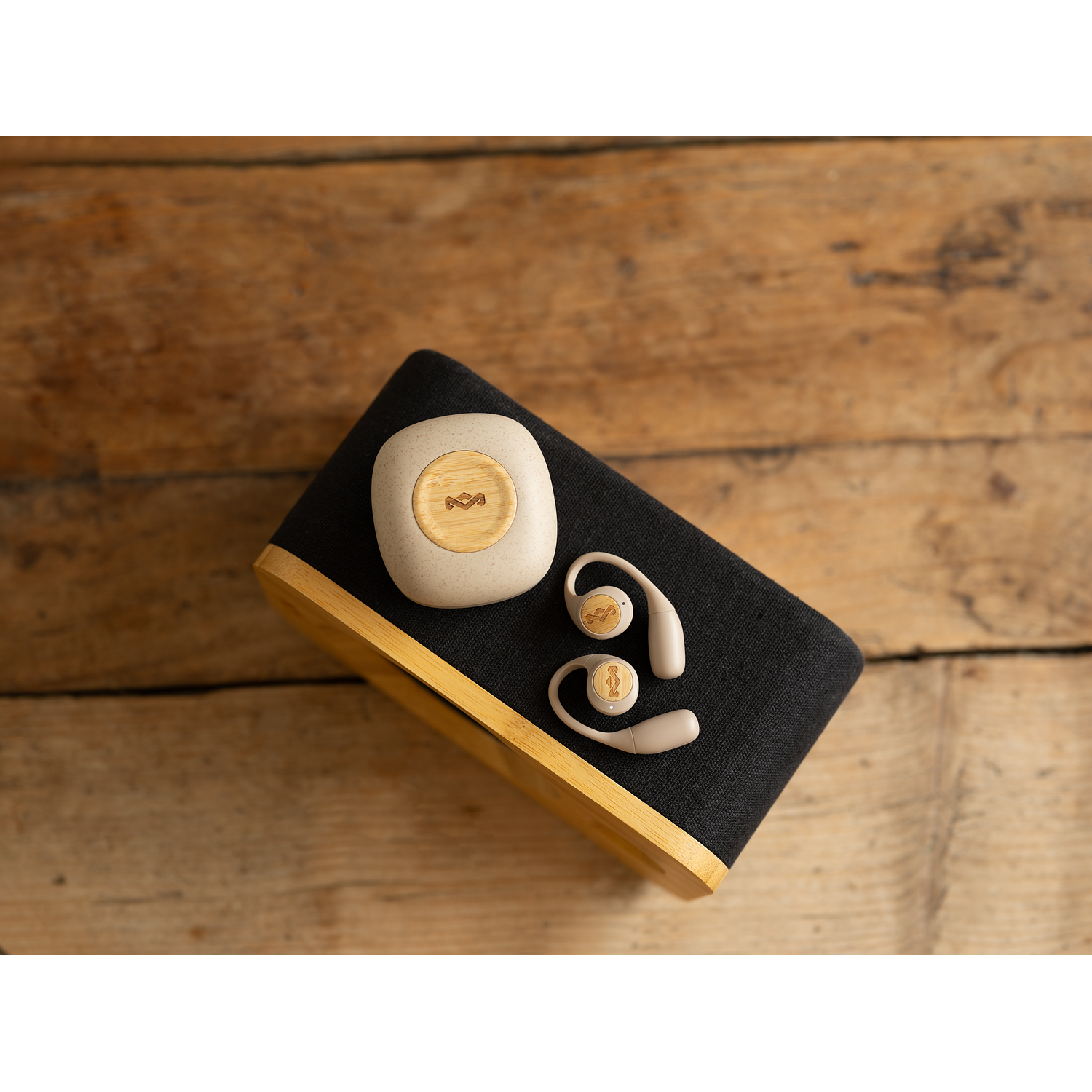 Wooden speaker with a case for earbuds and earbuds. The background is a wooden surface.