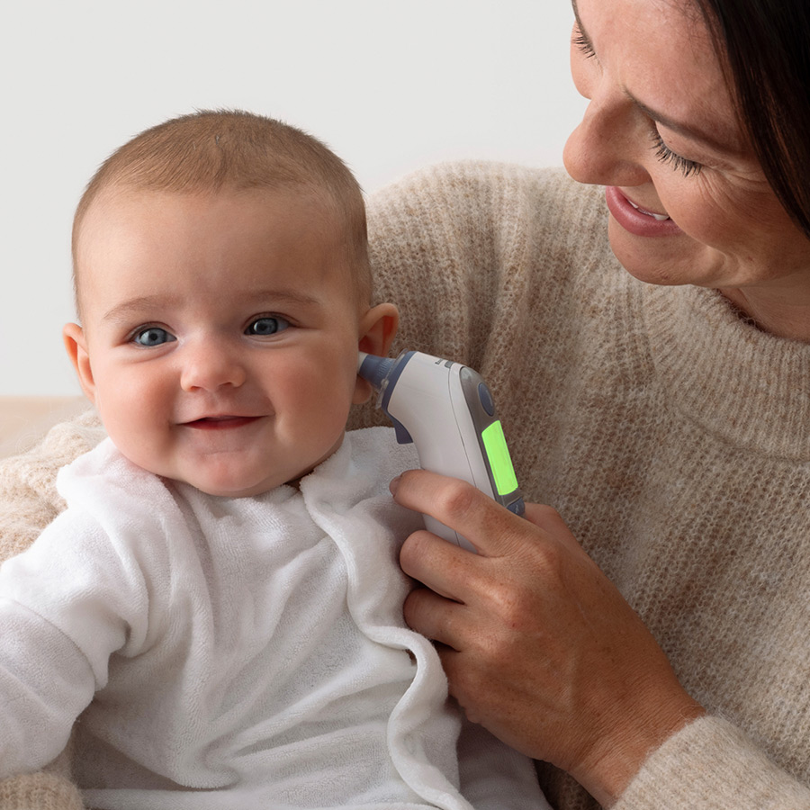 On vérifie la température d'un bébé avec un thermomètre auriculaire.