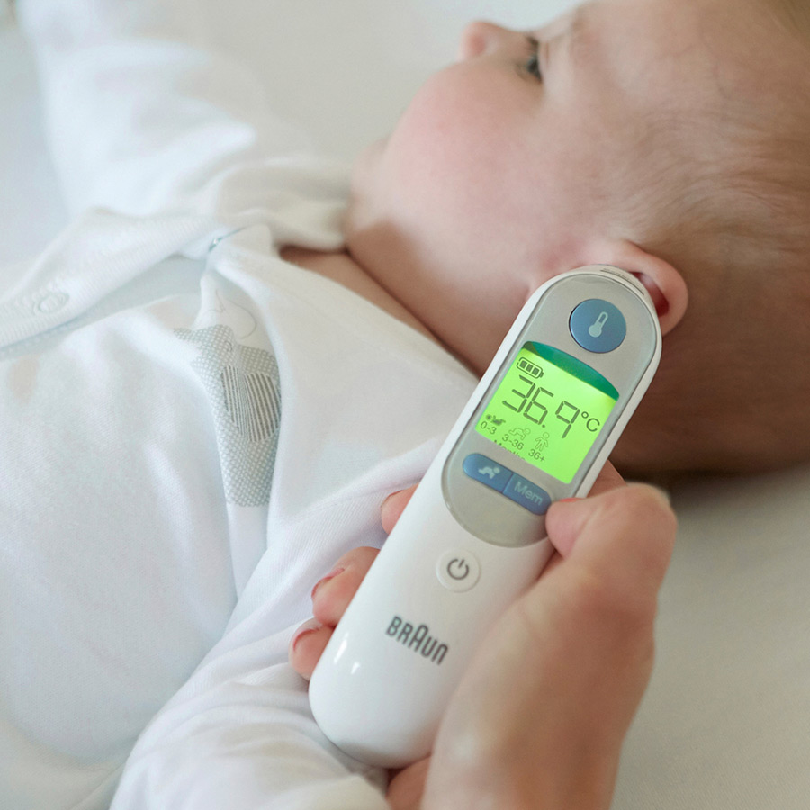 Tête de bébé et main tenant un thermomètre affichant 36,9°C sur l'écran.