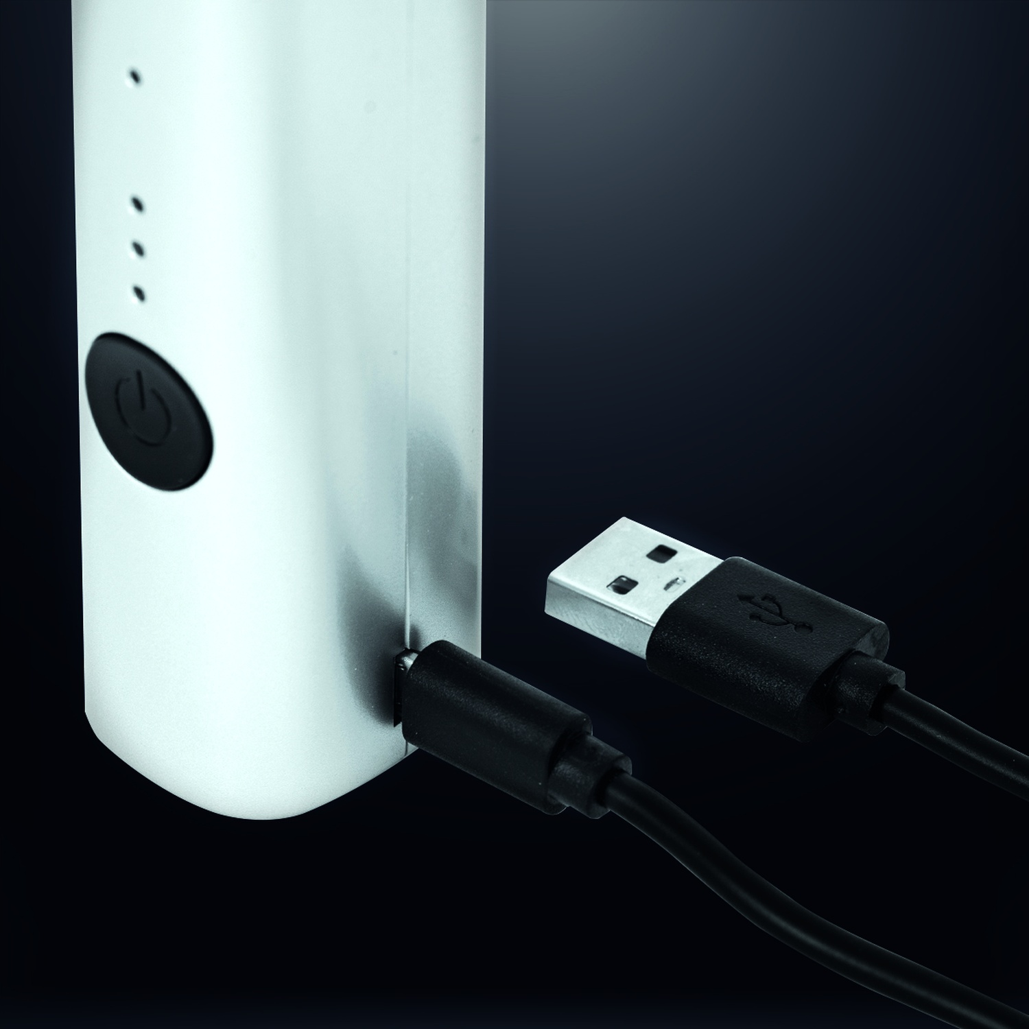 Un power bank argentato con un cavo USB nero collegato, sfondo nero.