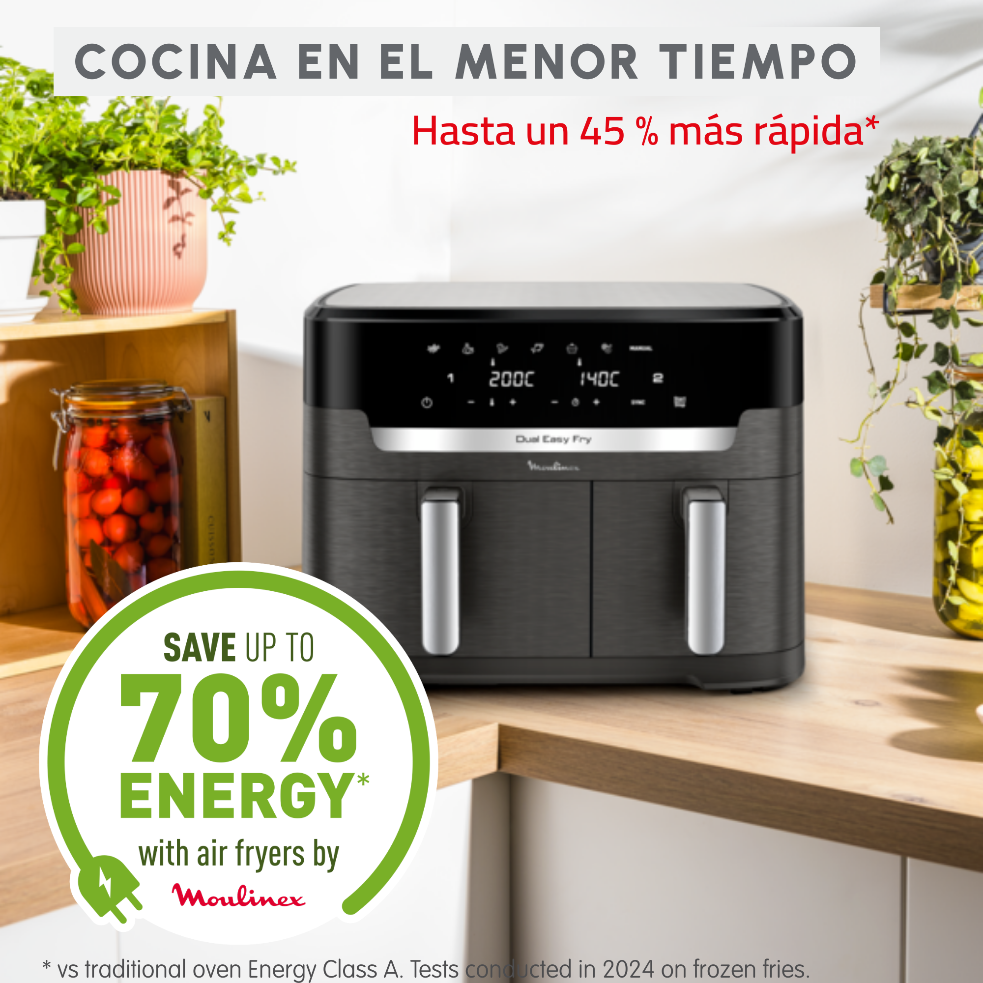 Freidora de aire negra y gris sobre una encimera de cocina con plantas y comida en el fondo.