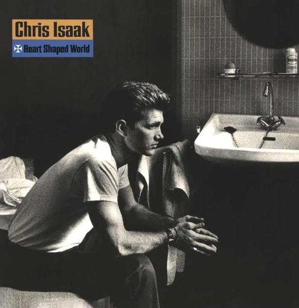 Une photo en noir et blanc d'un homme assis dans une salle de bain, un lavabo et un miroir en arrière-plan.