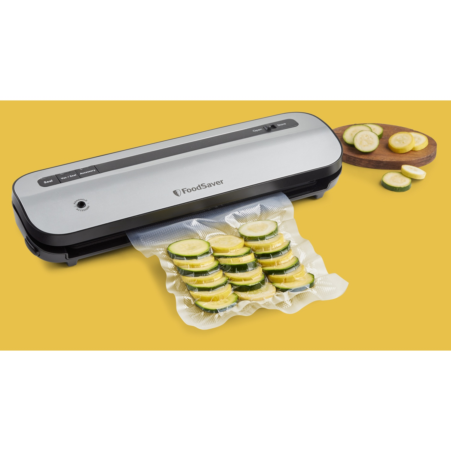 Macchina FoodSaver con fette di zucchine in sacchetto, su sfondo giallo con tagliere in legno.