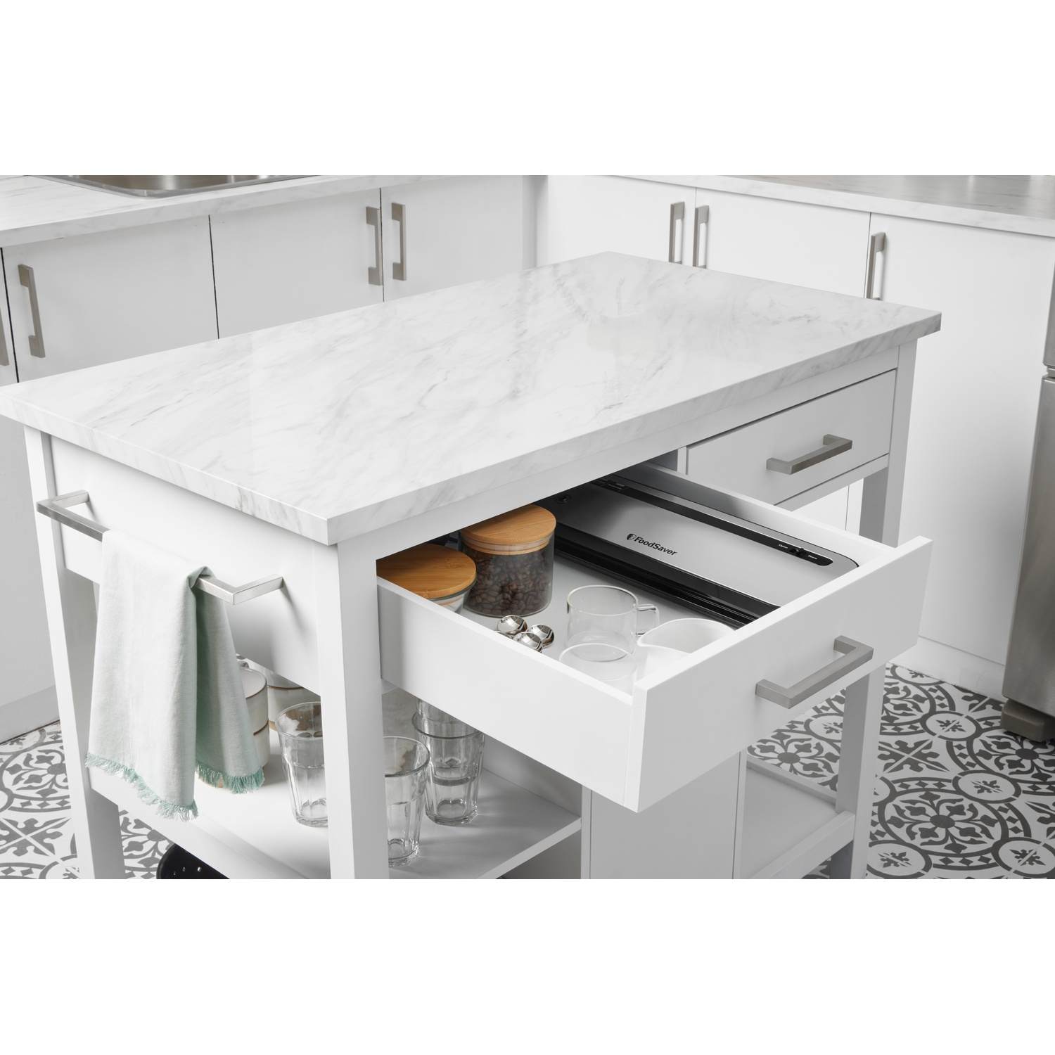 Un'isola cucina bianca con piano in marmo, cassetto aperto con sigillatrice per alimenti.
