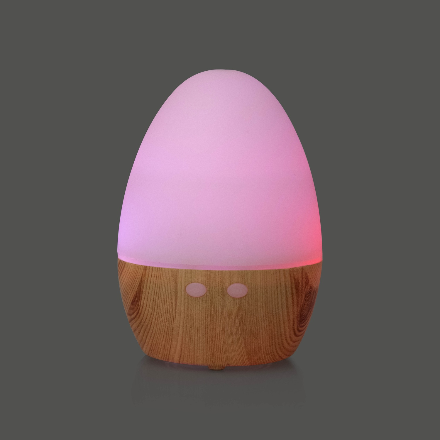 Un diffusore di aromi a forma di uovo, con base in legno, che brilla di luce rosa. Sfondo grigio.