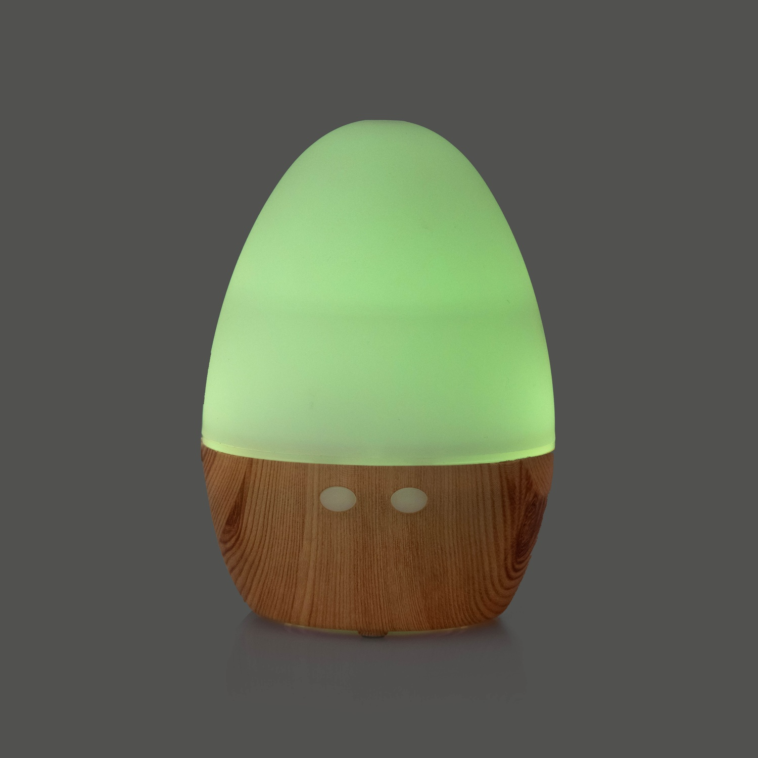 Diffusore di aromi a forma di uovo, bagliore verde dall'alto, base in legno, su superficie grigia.