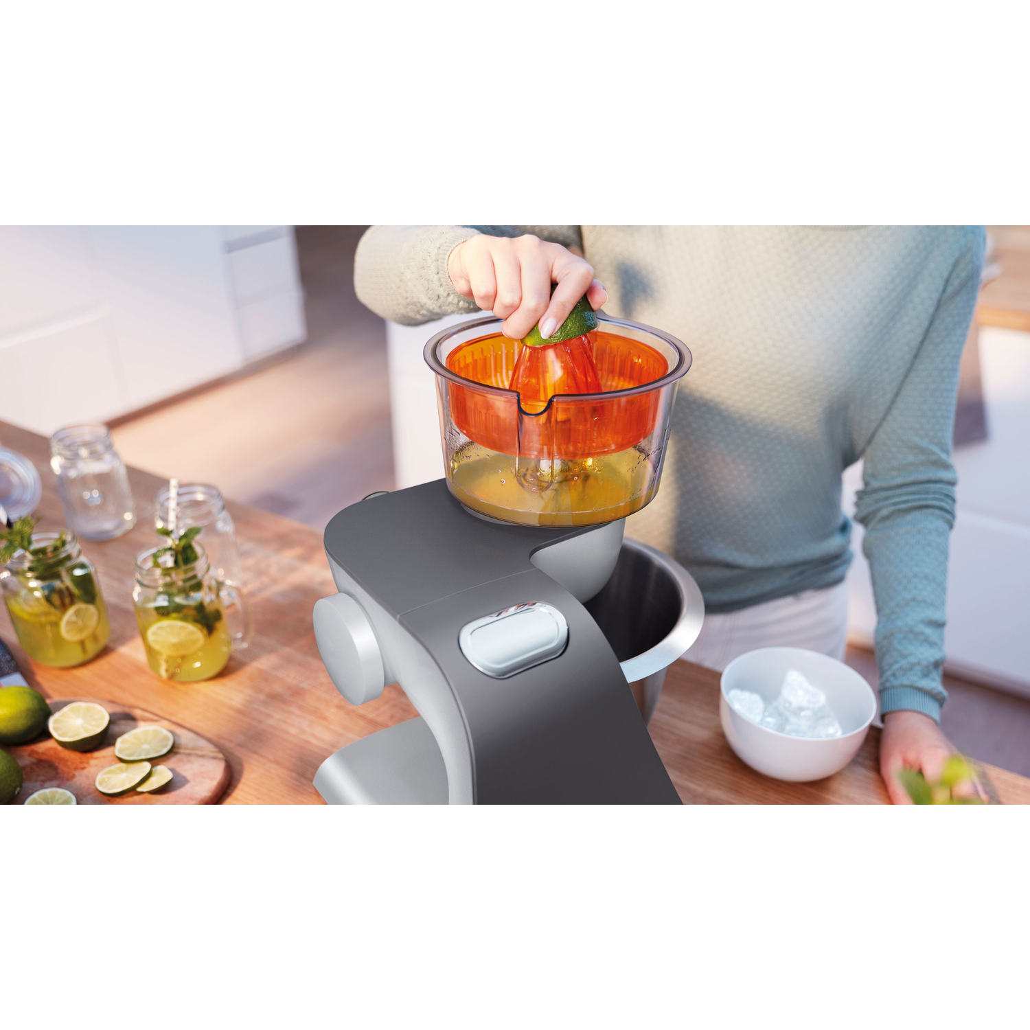 Une personne qui presse une orange dans une cuisine à l'aide d'un presse-agrumes gris.