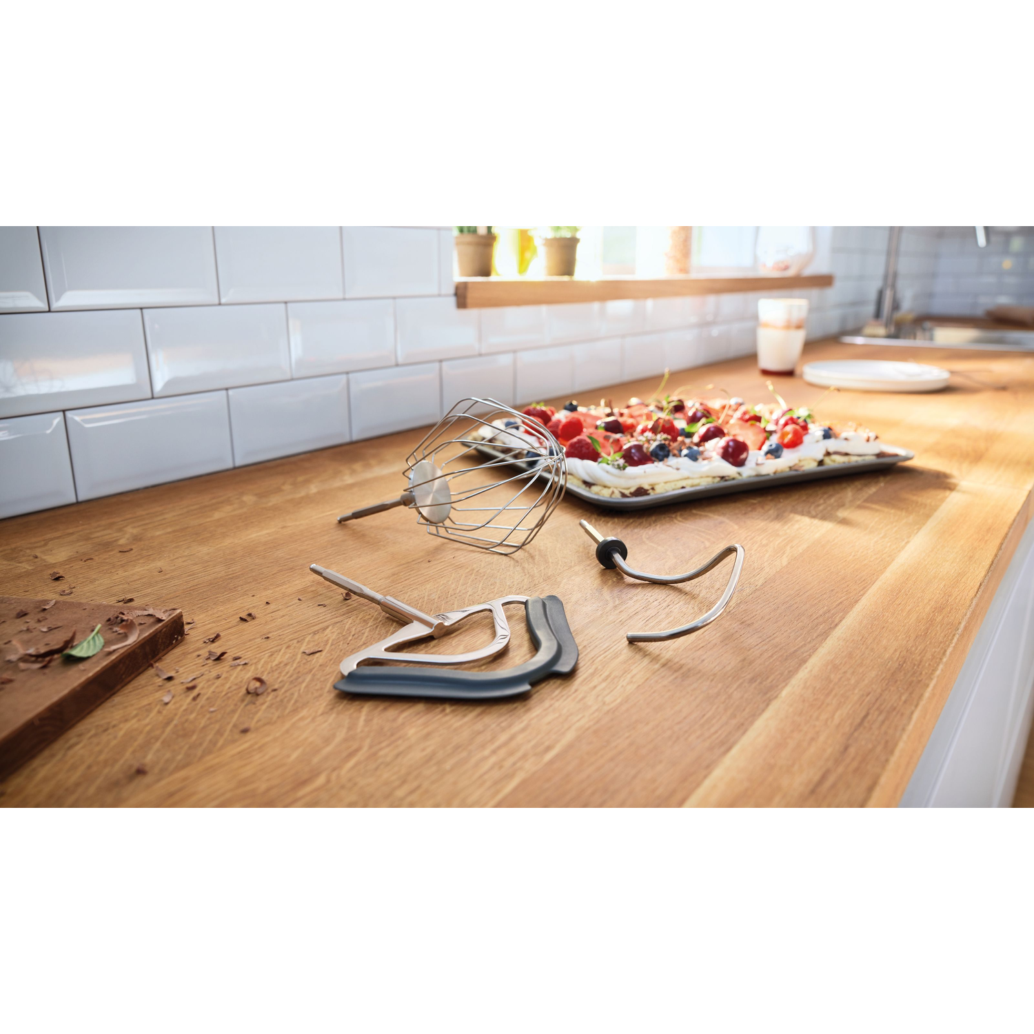 Ustensiles de cuisine sur un comptoir en bois. Un dessert en arrière-plan.