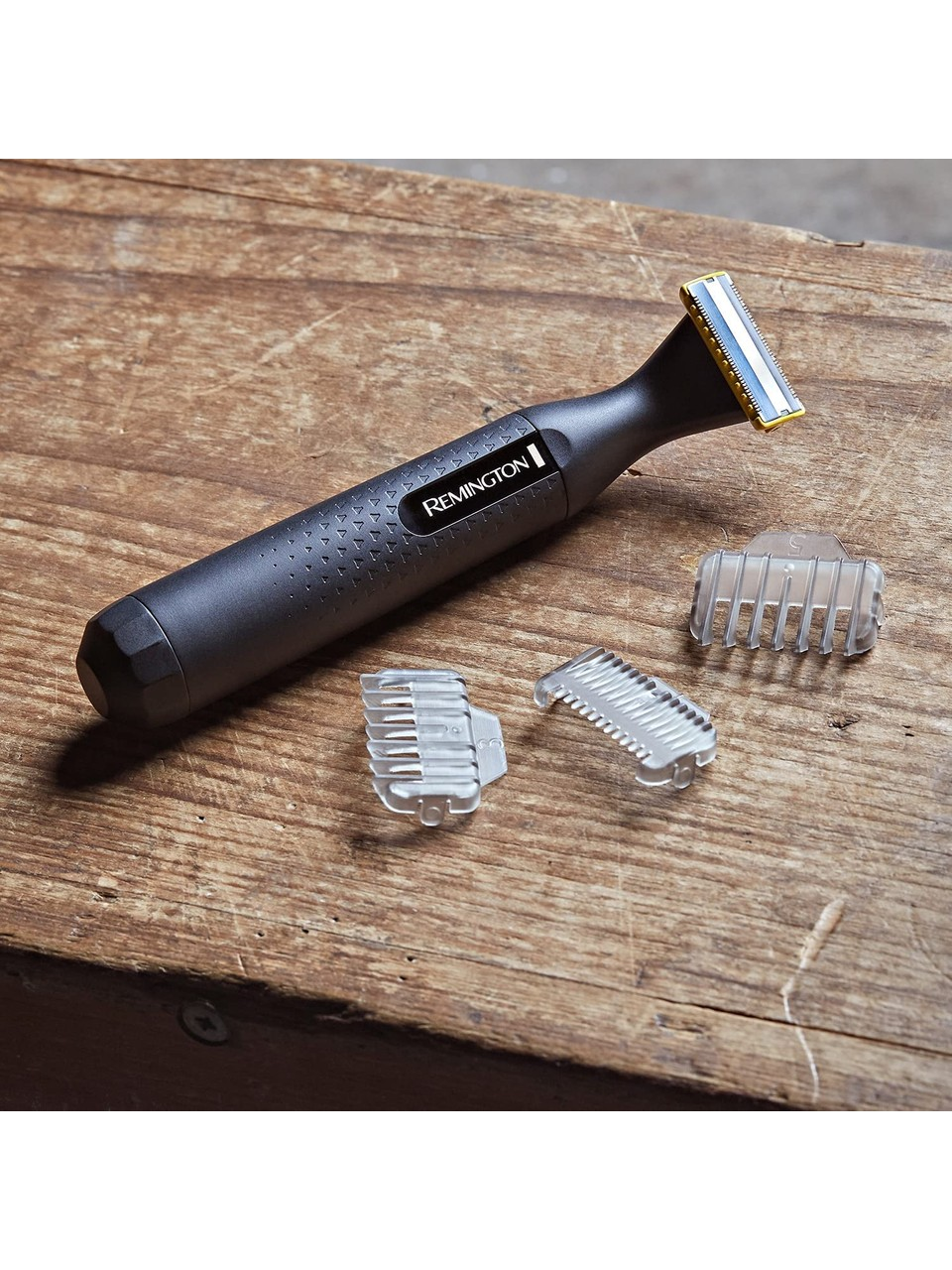 Remington sakal kesme makinesi, üç şeffaf plastik ataşmanla, ahşap bir yüzeyde.