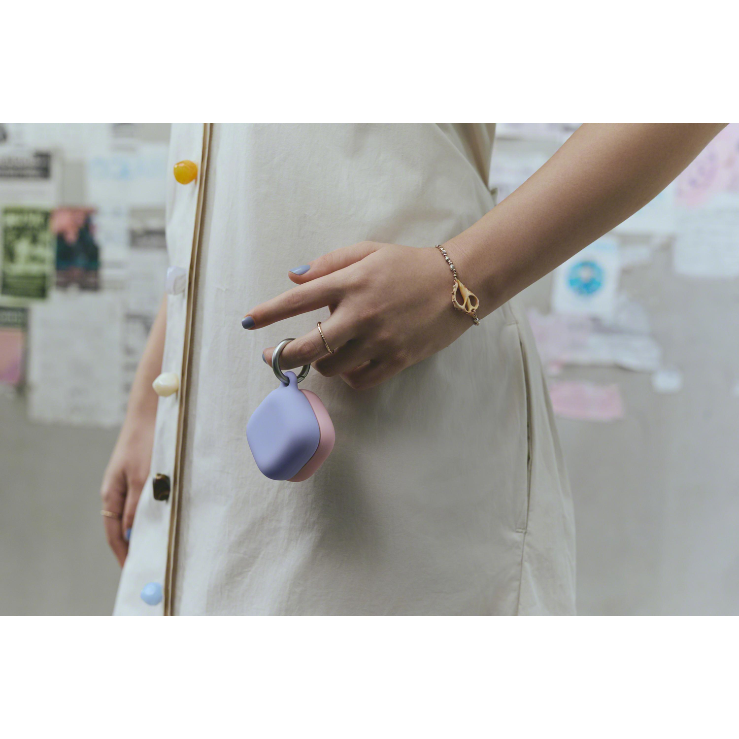 Une personne tenant un petit étui bicolore avec un bracelet. L'arrière-plan comprend des affiches colorées.