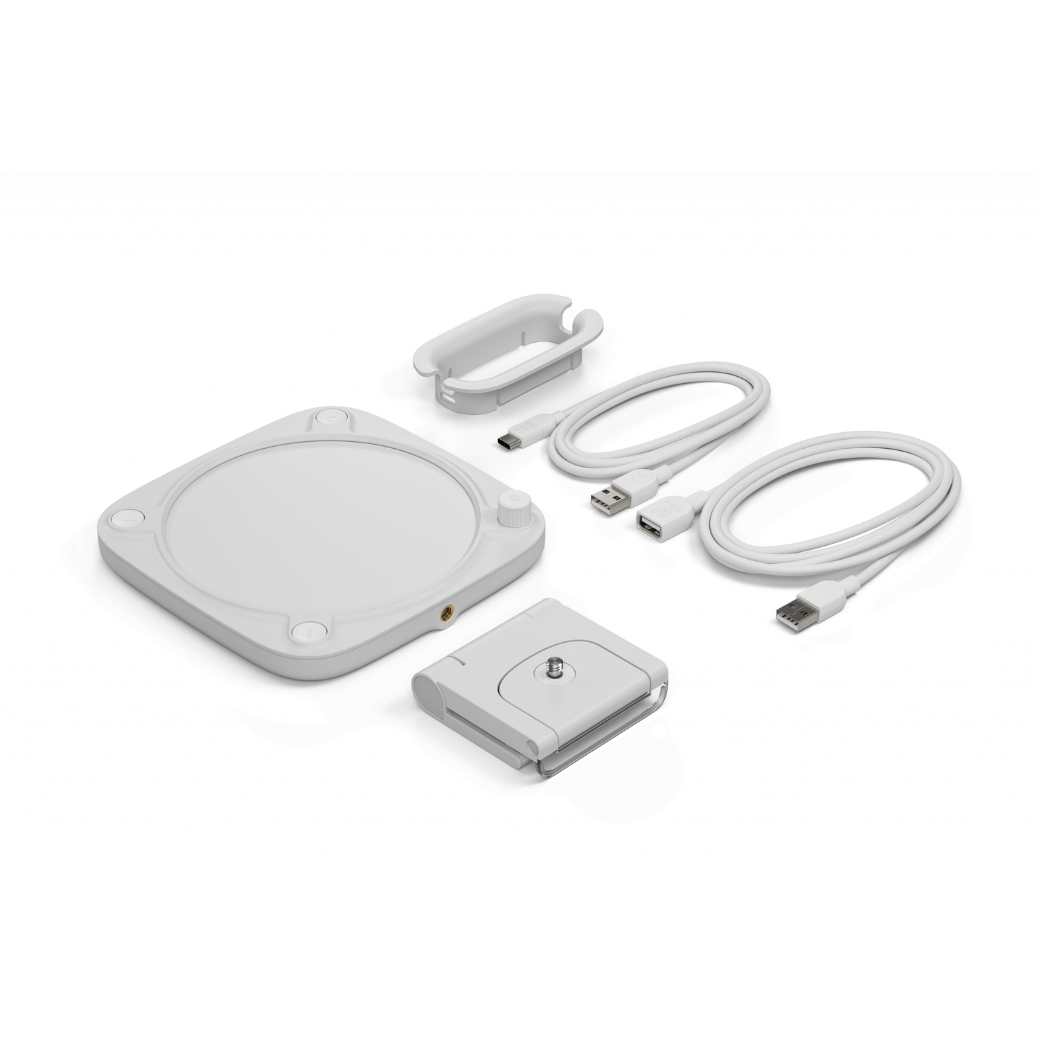A white circular device with components including cables, a mount, and a holder, on a white surface.