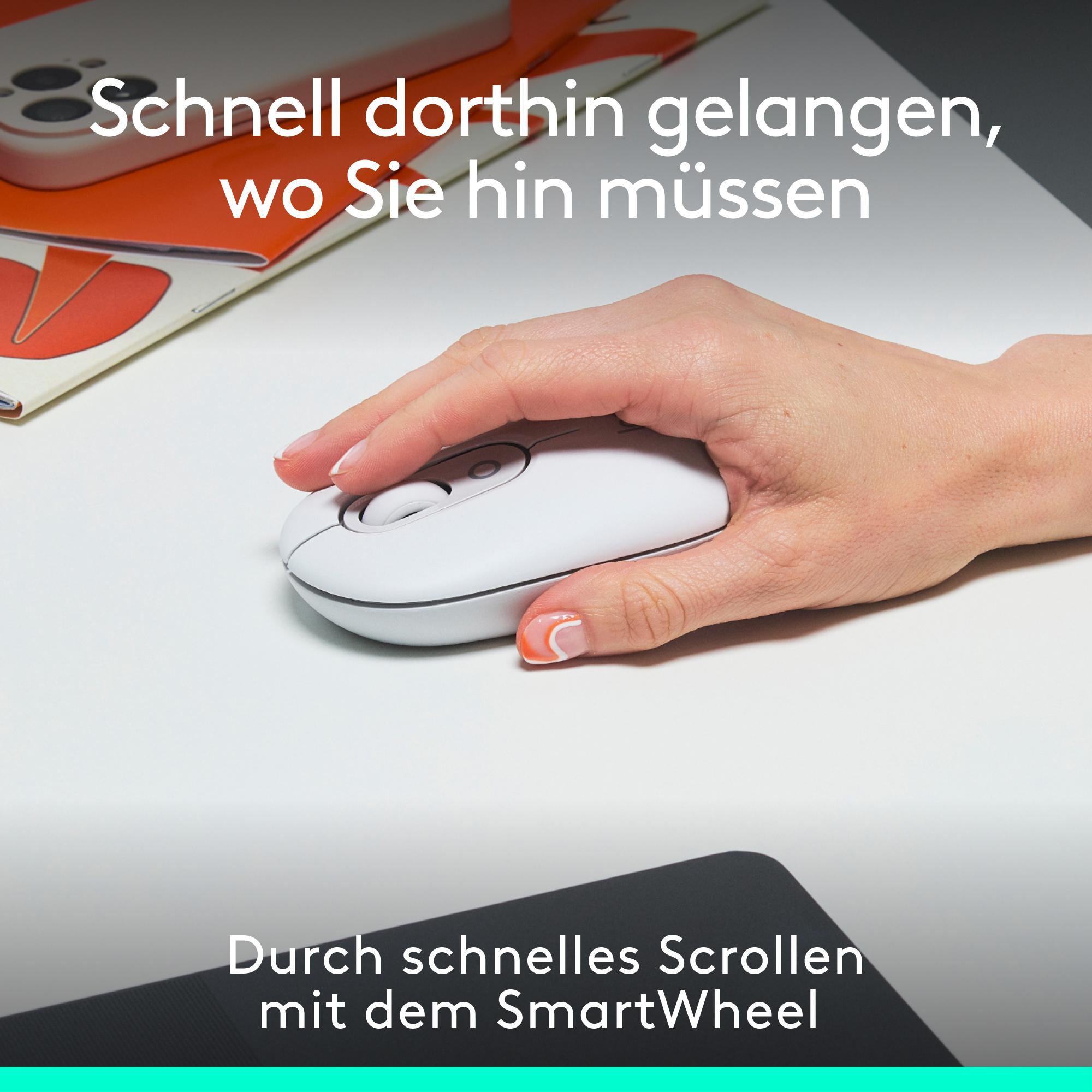 Eine Hand, die eine weiße Computermaus hält. Die Maus befindet sich auf einer weißen Oberfläche. Der Hintergrund ist ein Schreibtisch.
