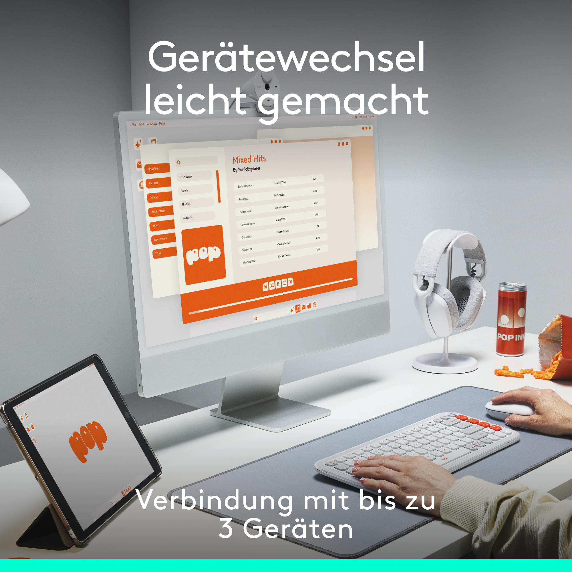 Ein Schreibtisch mit Monitor, Tablet, Kopfhörern und einer Dose Soda. Text auf Deutsch.