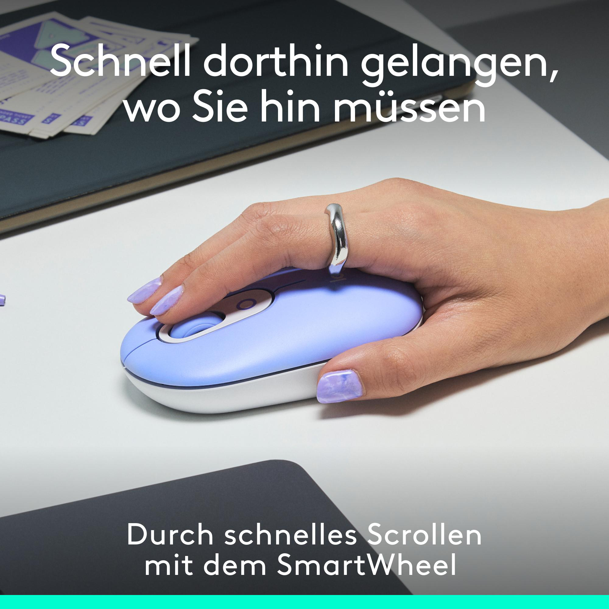 Eine Hand benutzt eine hellblaue Maus auf einem weißen Schreibtisch. Ein Ring befindet sich an der Hand.