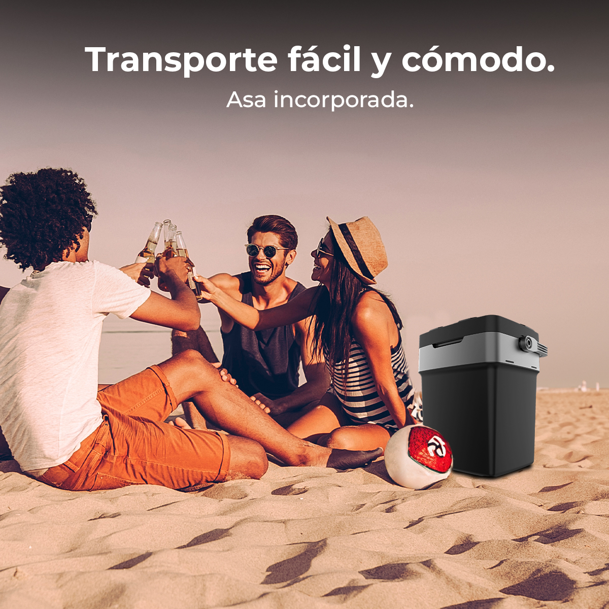 Amigos brindando con cerveza en la playa, con nevera y balón cerca, día soleado.