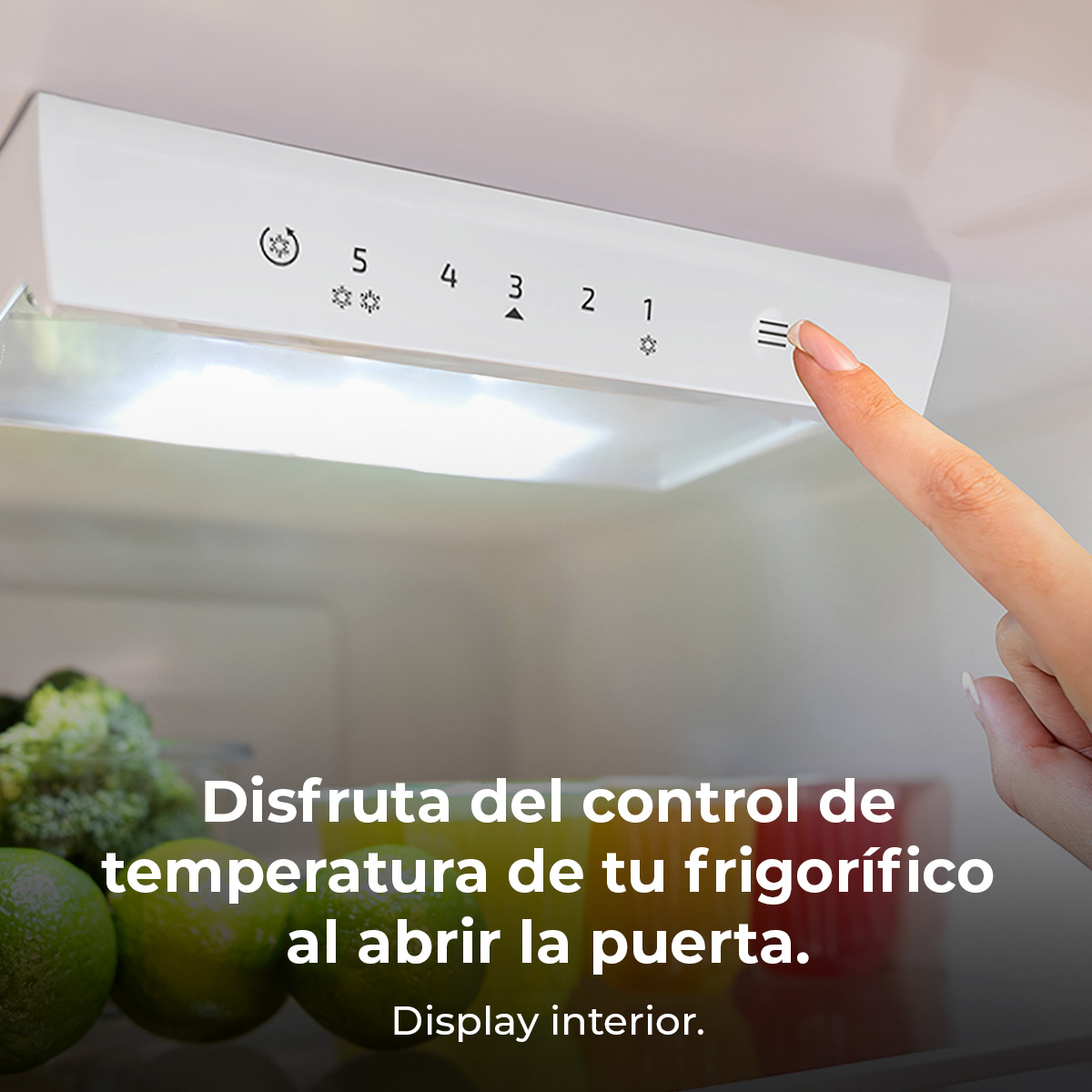 Mano de mujer señalando un panel de control del refrigerador. Texto en español.