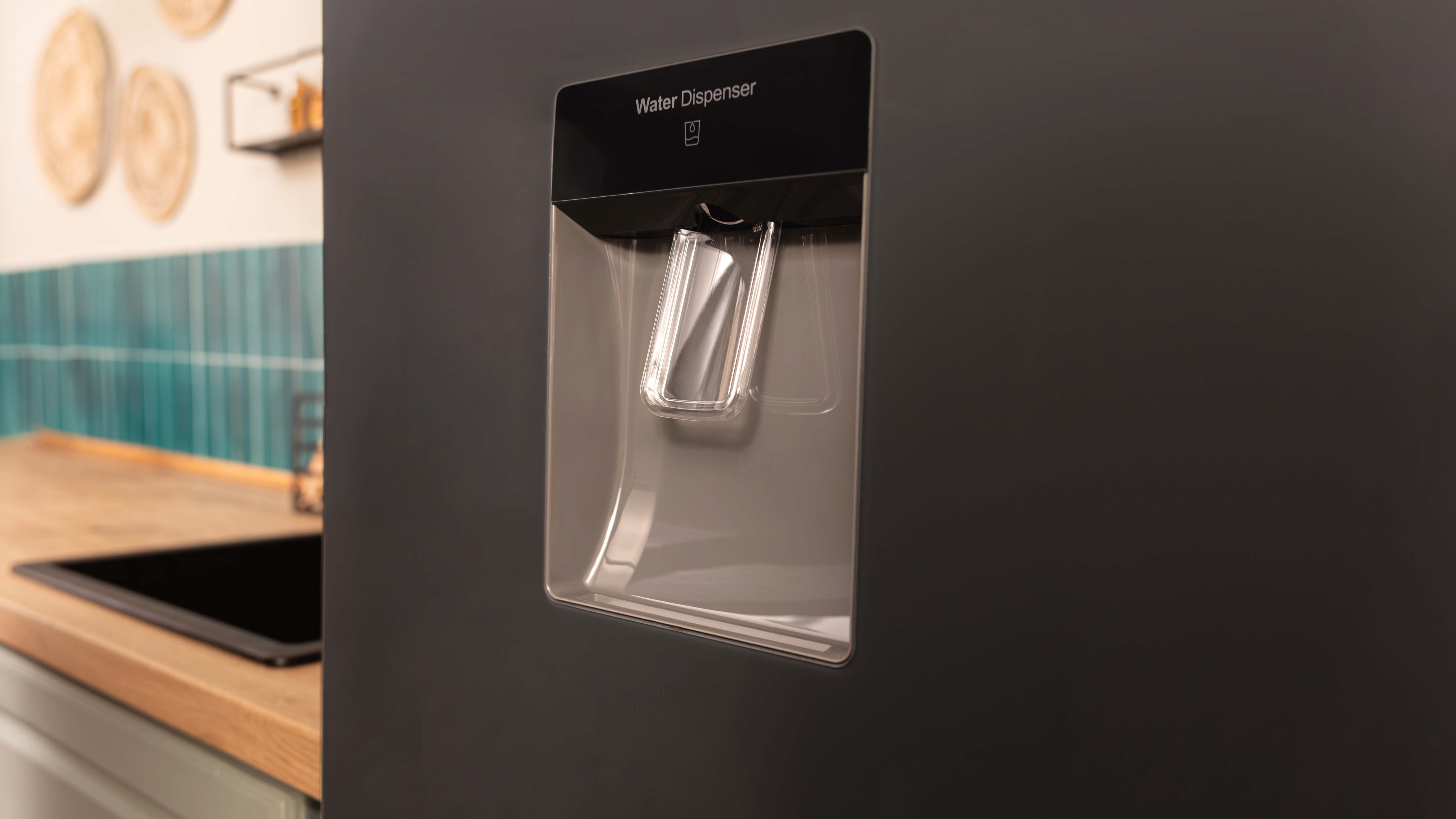 Primer plano de un dispensador de agua de un refrigerador negro. El dispensador está abierto y listo para dispensar agua.