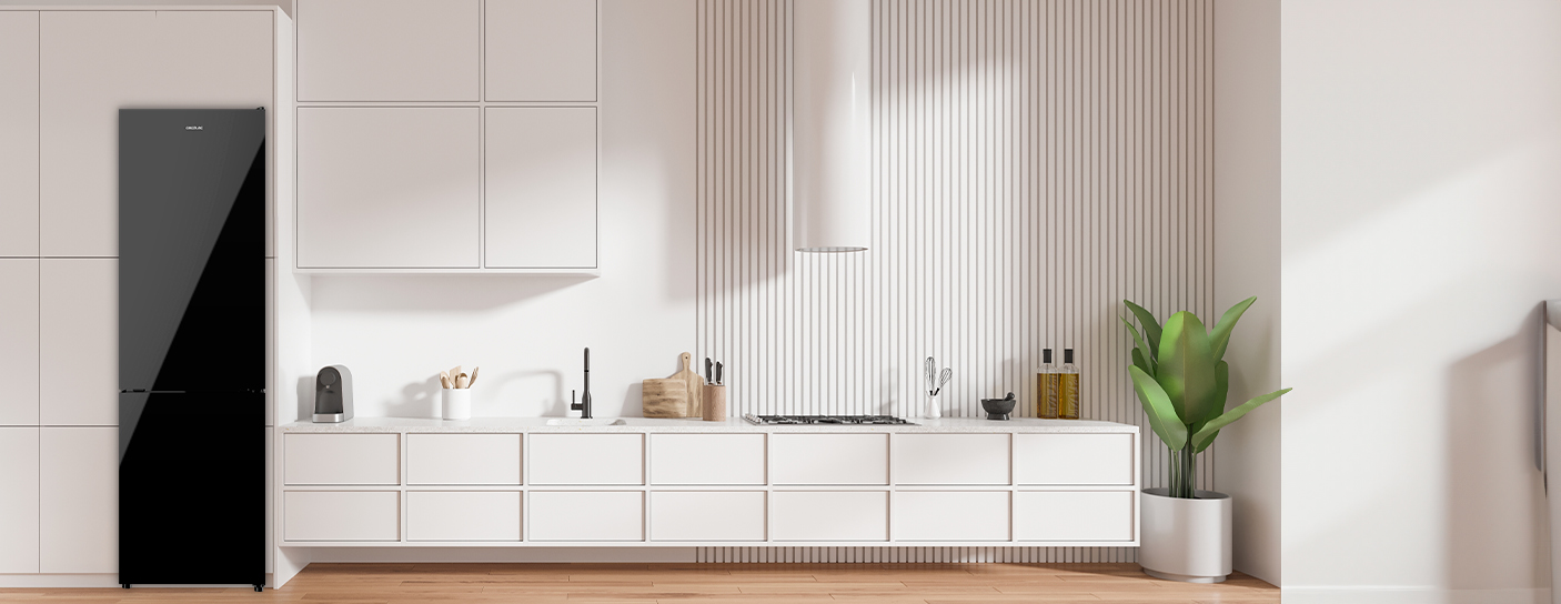 Cocina moderna con refrigerador negro, gabinetes blancos y una planta.