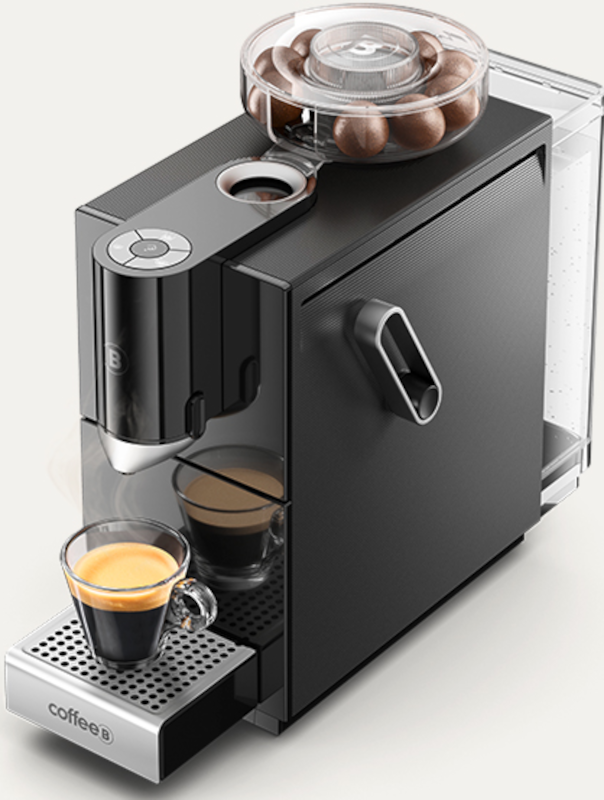 Eine schwarze Espressomaschine mit einem Glas Kaffee und Kaffeebohnen.