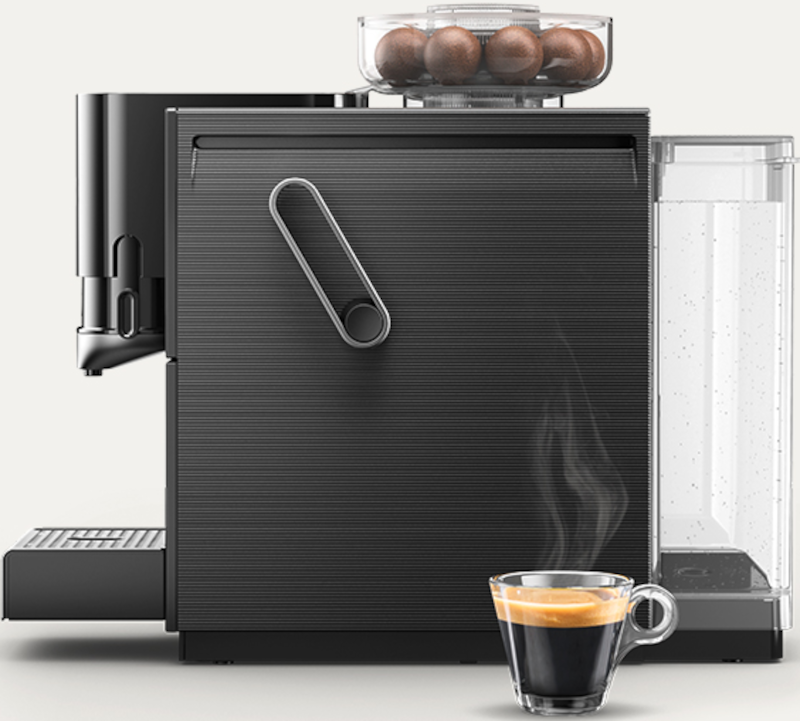 Eine schwarze Kaffeemaschine mit Kaffeeglas und Bohnenbehälter. Dampf steigt vom Kaffee auf.