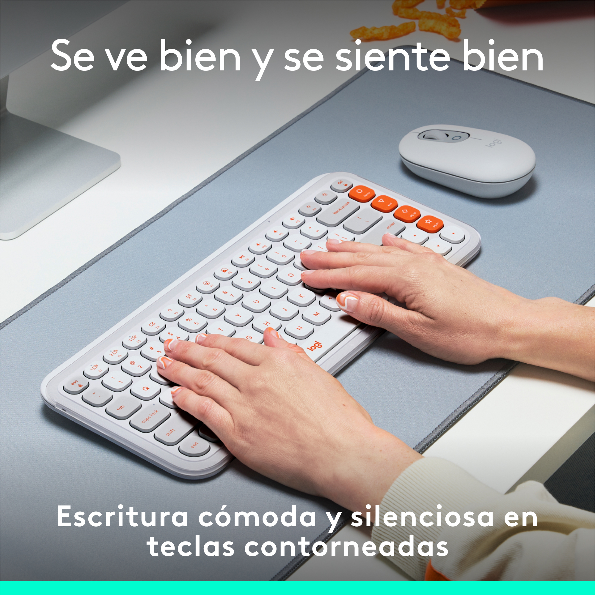 Manos escribiendo en un teclado blanco con teclas naranjas, un ratón blanco sobre una alfombrilla gris.