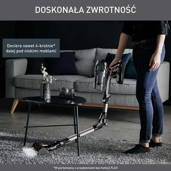 Kobieta odkurza pokój elastycznym odkurzaczem, w pobliżu sofy.