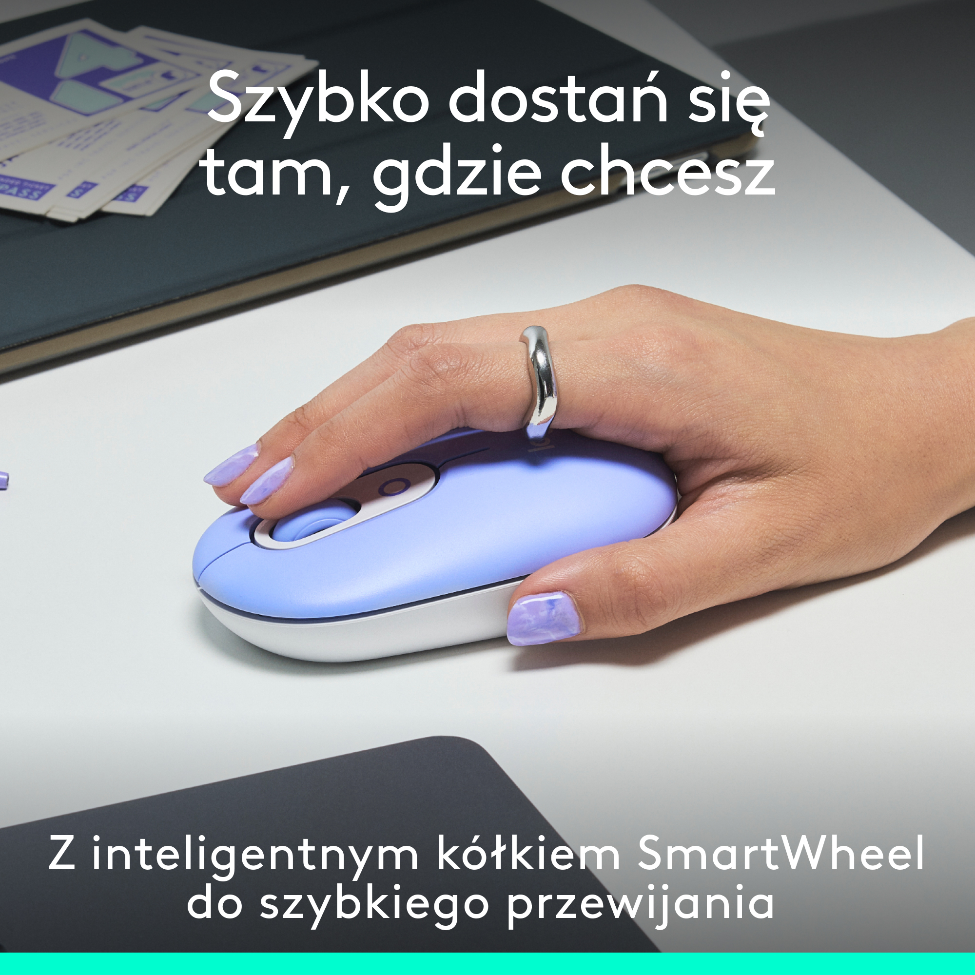 Dłoń używająca niebieskiej myszy na biurku. Widoczny tekst i pierścionek.