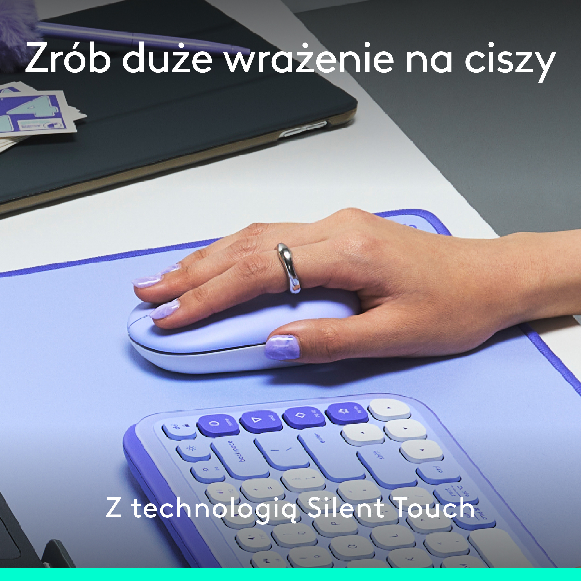 Dłoń osoby z pierścionkiem na fioletowej podkładce pod mysz, klawiatura widoczna poniżej.