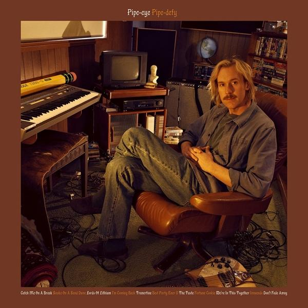 Albumcover: Mann in einem Raum mit Keyboard, Schreibtisch und altem Fernseher. Albumname ist 'Pipe-eye'.