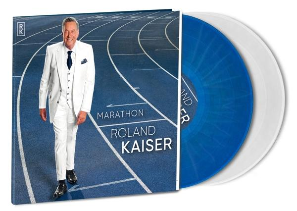 Albumcover mit Mann im weißen Anzug. Zwei blaue und weiße Vinylplatten. Weißer Hintergrund.