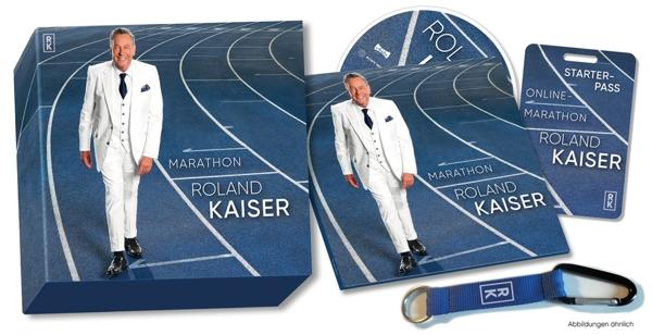 Bild zeigt Albumcover und Merchandise von Roland Kaiser, einem Mann in weißem Anzug.