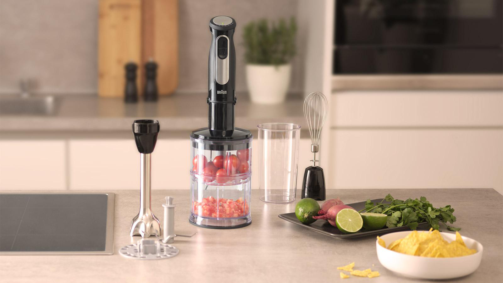 Mixer mit Tomatenmischung und separaten Teilen auf einer Küchenarbeitsplatte mit Zutaten.