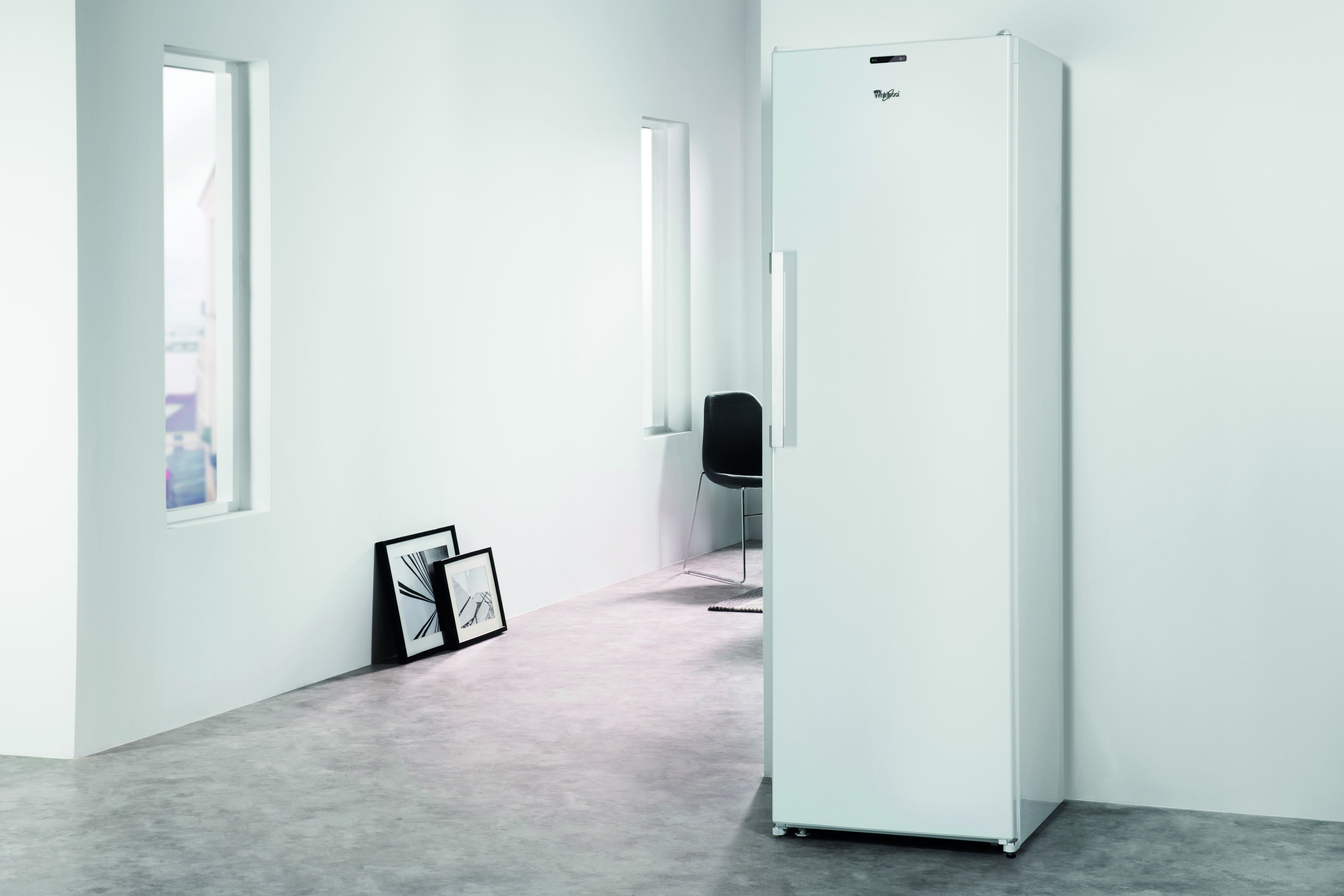 Biała lodówka stojąca w minimalistycznym białym pokoju.