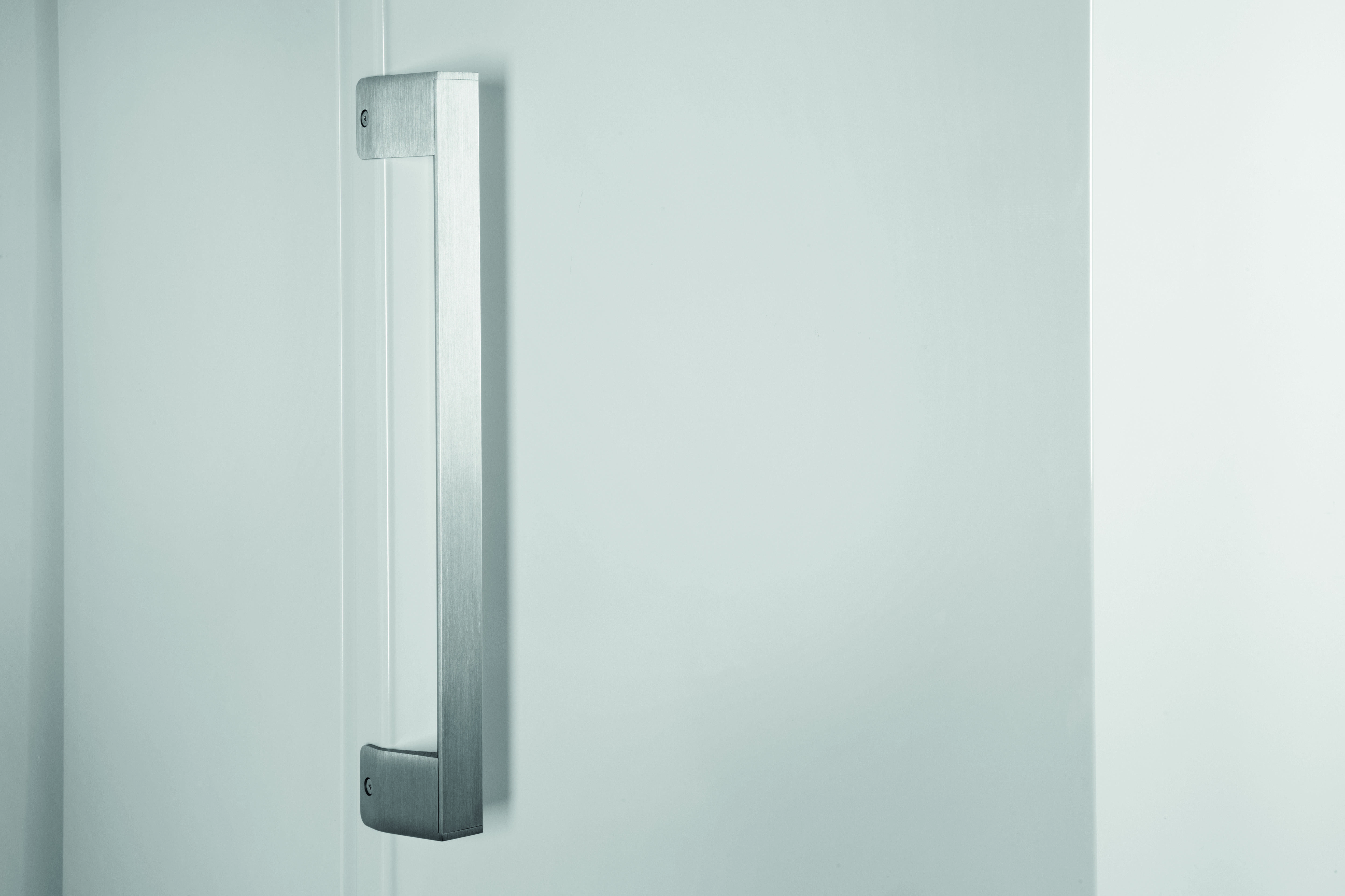 Srebrna klamka na białych drzwiach. Minimalistyczny design z czystym tłem.