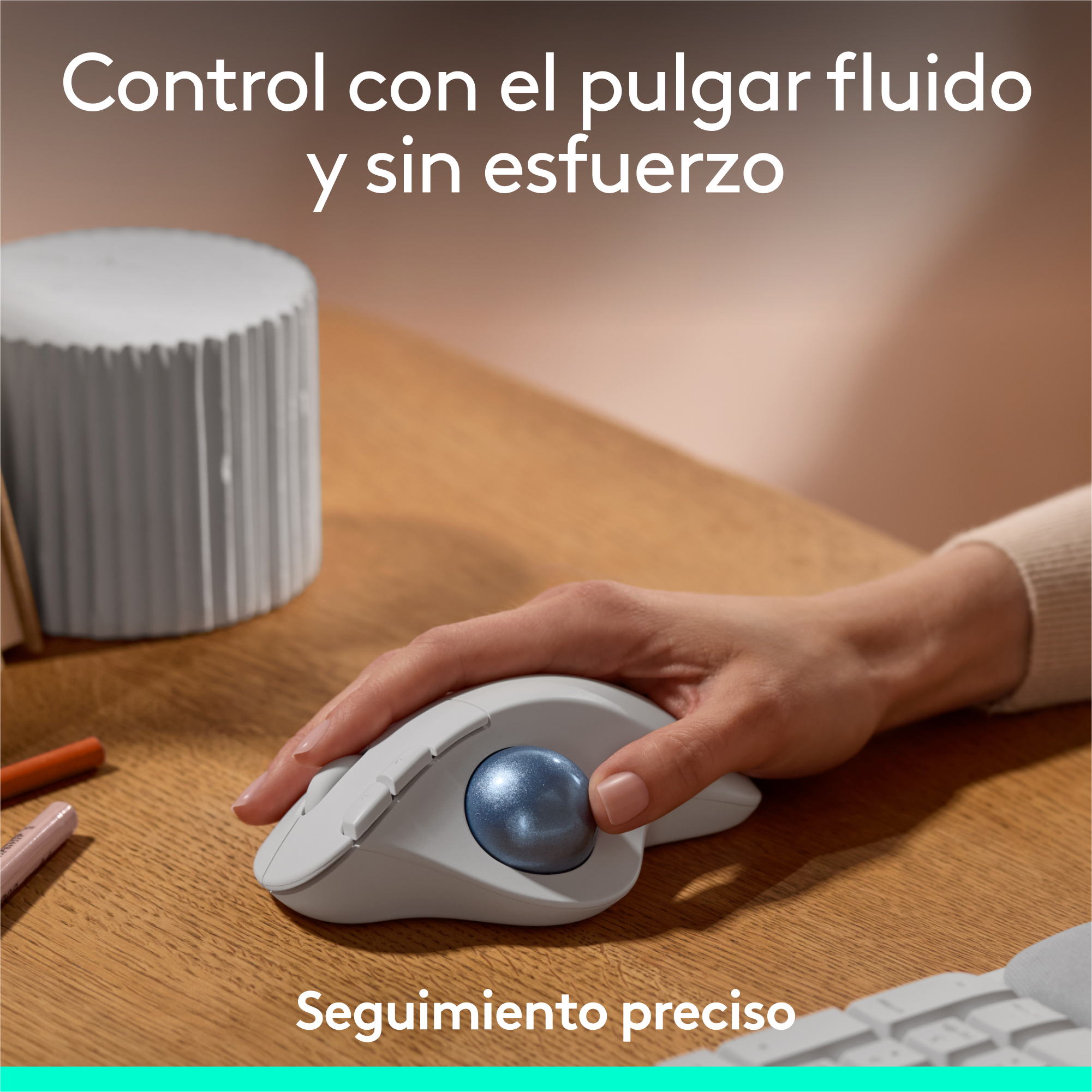 La mano de una persona usando un ratón trackball blanco y azul sobre un escritorio de madera.