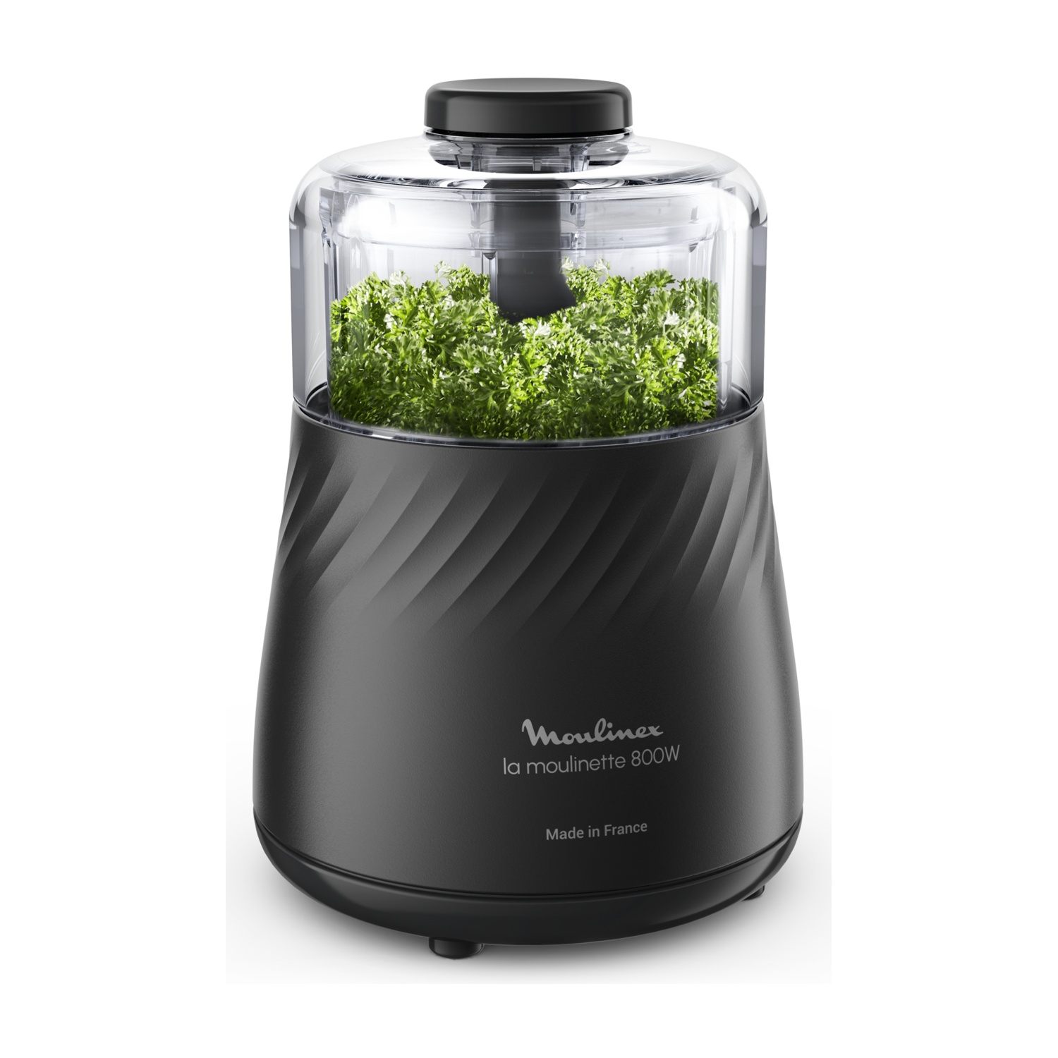 Tritatutto Moulinex nero con prezzemolo all'interno. Coperchio trasparente e base nera. Lo sfondo è bianco.