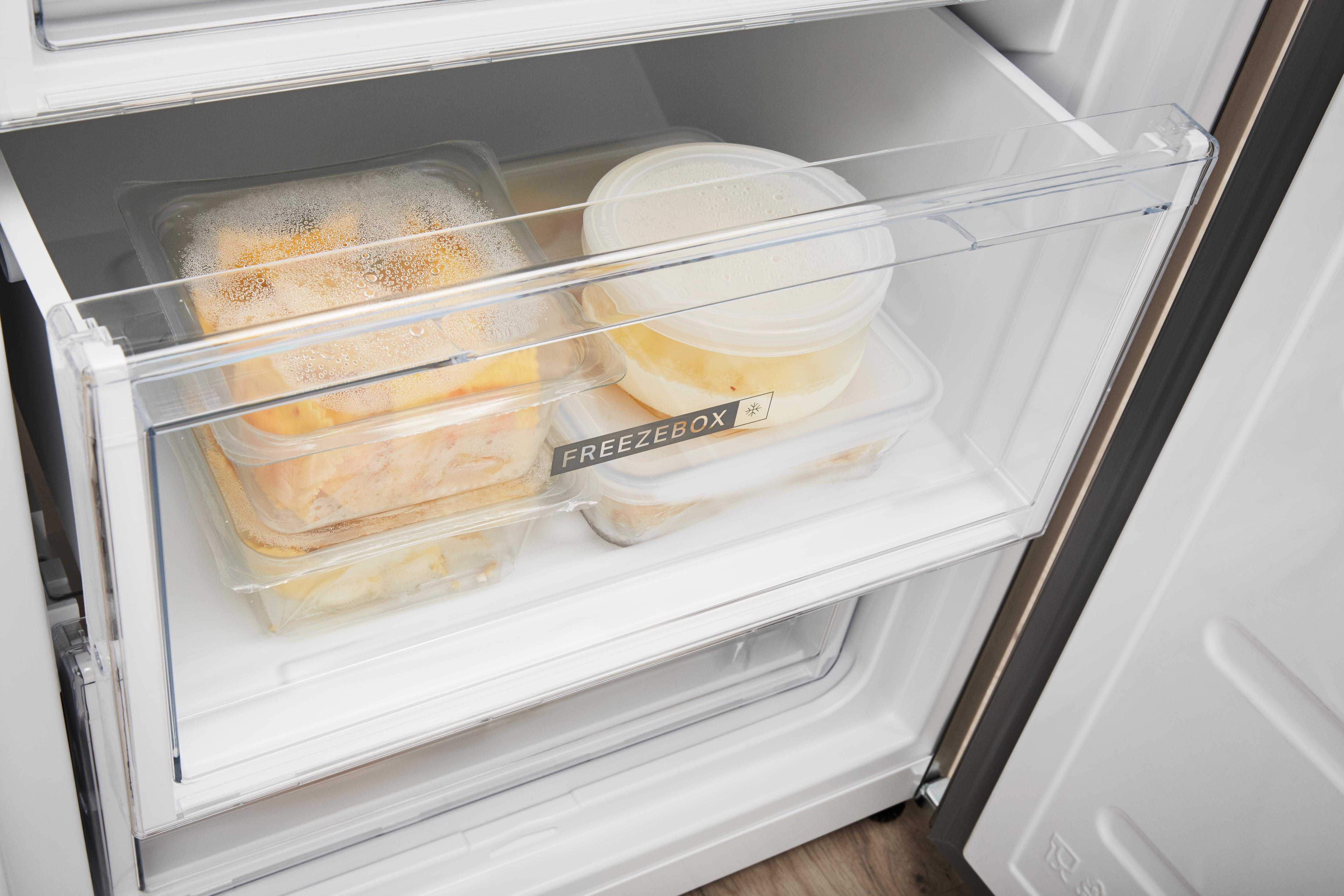 Szuflada zamrażarki z przezroczystymi pojemnikami na żywność. Zamrażarka jest otwarta.