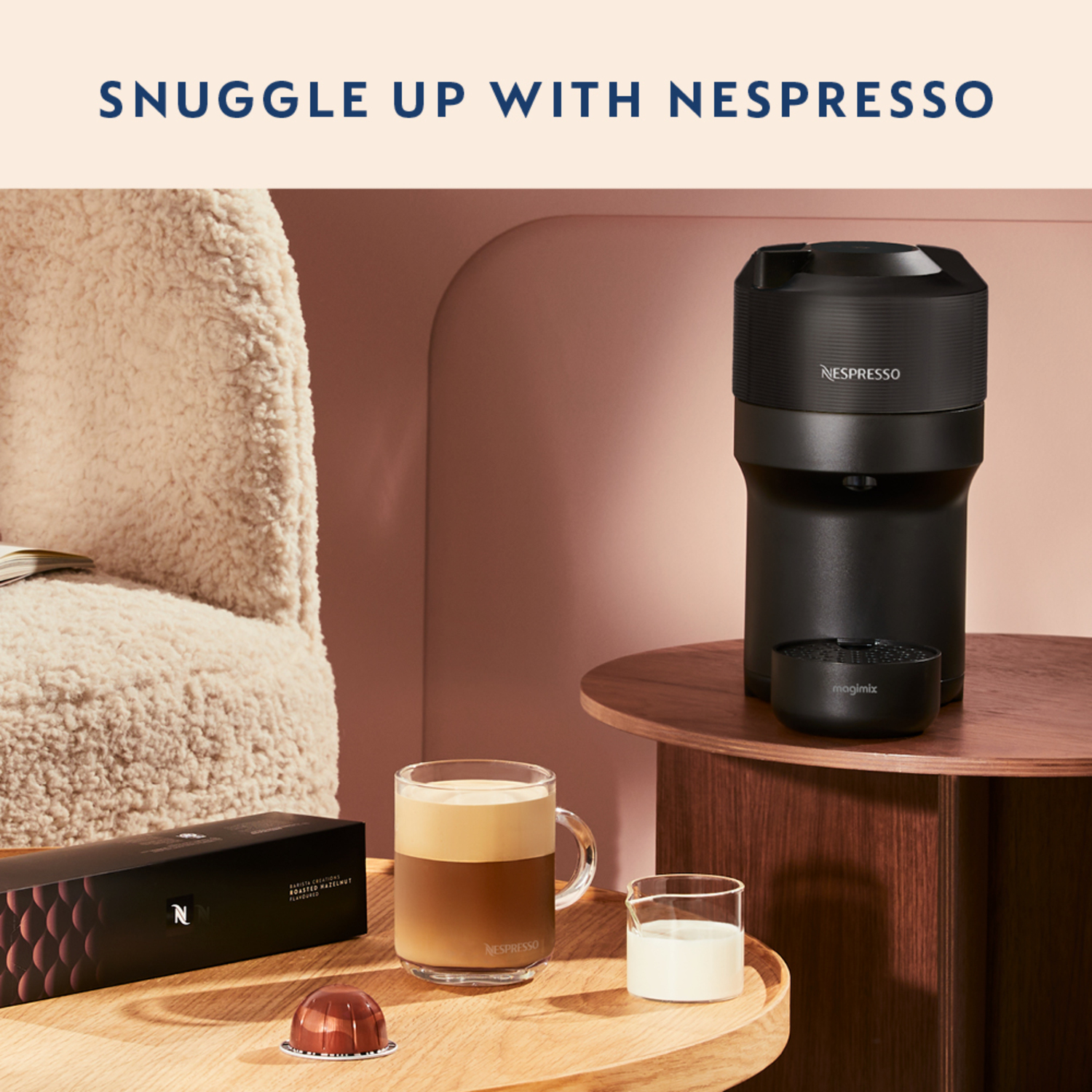 Nespresso coffee machine with coffee in a glass, milk, and capsules on a table.
