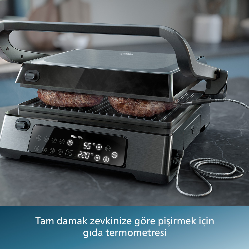 İki hamburgerli bir Philips ızgara açık. Izgarada dijital bir ekran var. Tezgah koyu gri.
