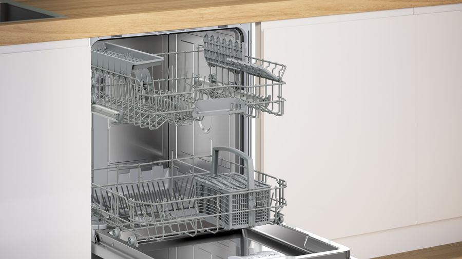 Un lavavajillas abierto con estantes vacíos adentro, contra un fondo de cocina.